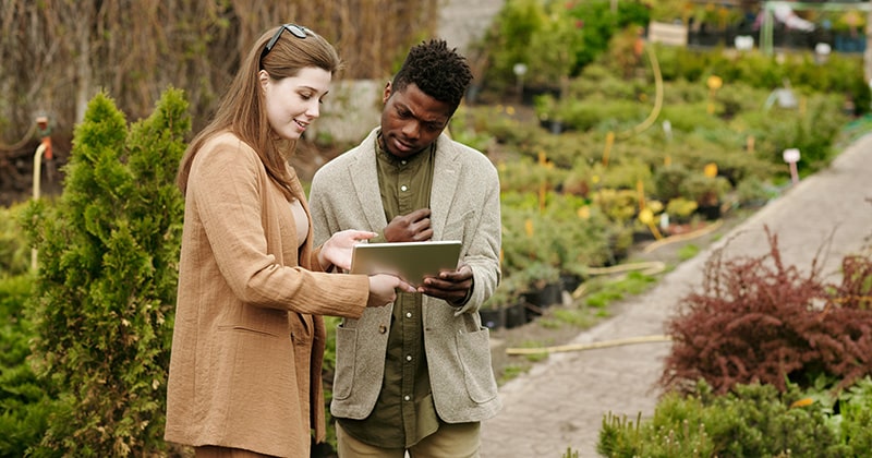 Female landscaper showing male customer information on tablet