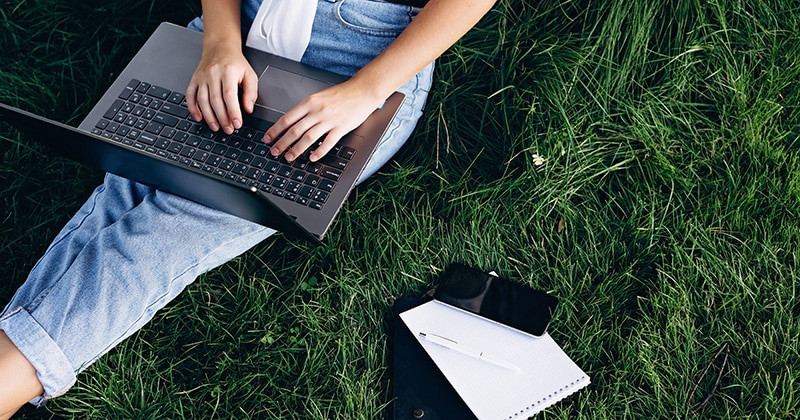 person-sitting-in-grass-on-laptop